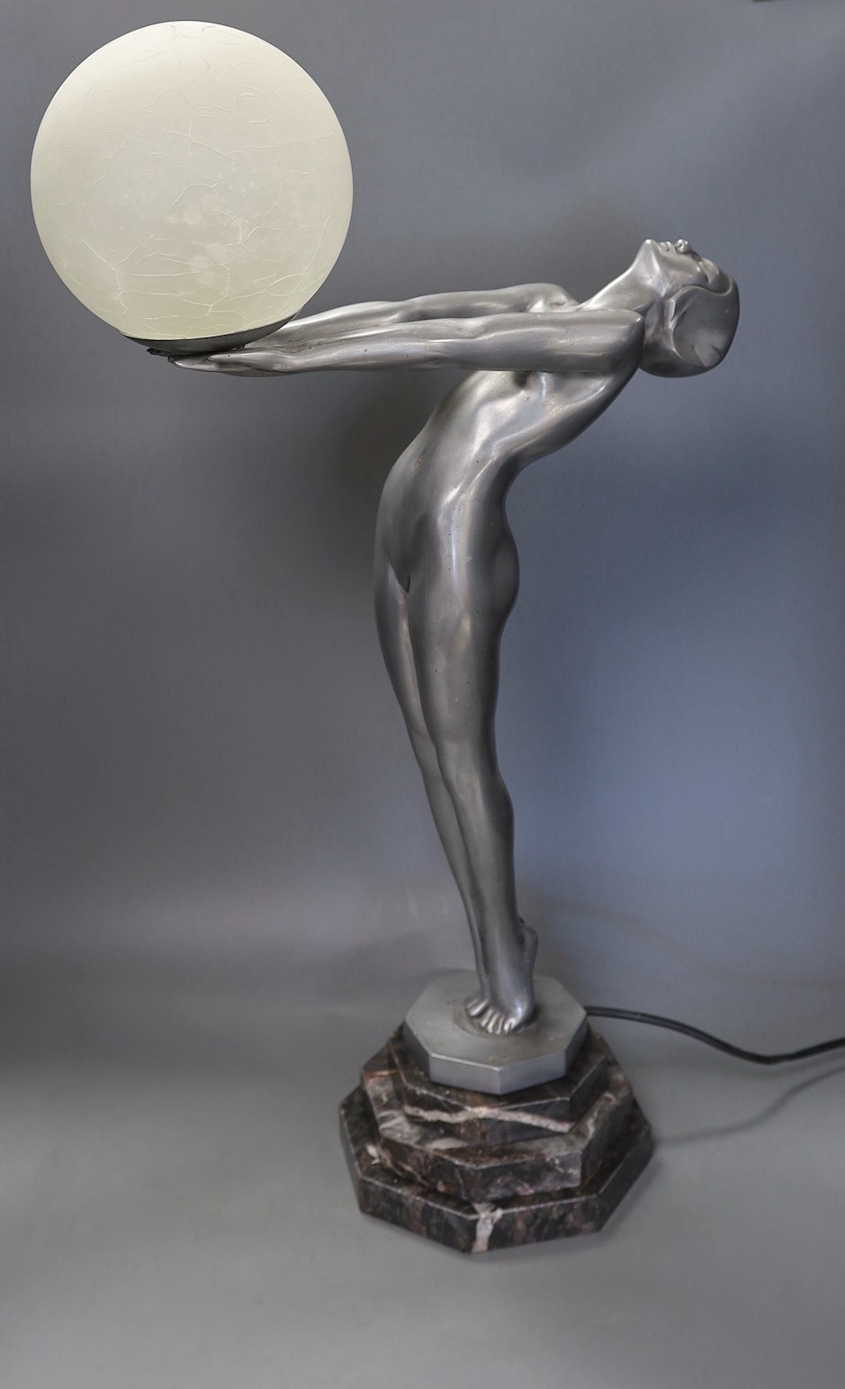 An Art Deco style figurative lamp of a lady holding a frosted glass globe, 66cms high.
